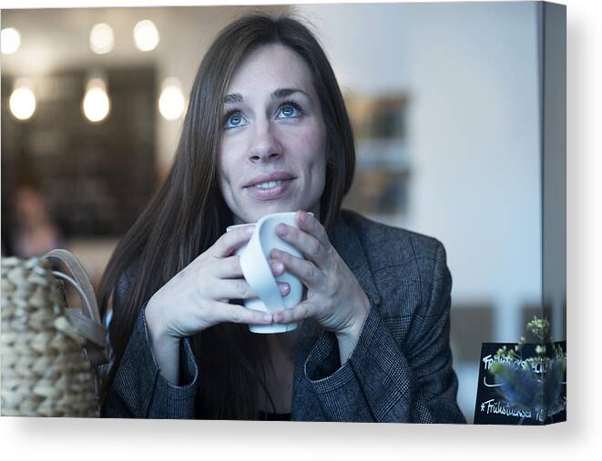 People Canvas Print featuring the photograph Young woman looking up whilst drinking coffee in cafe by Sigrid Gombert