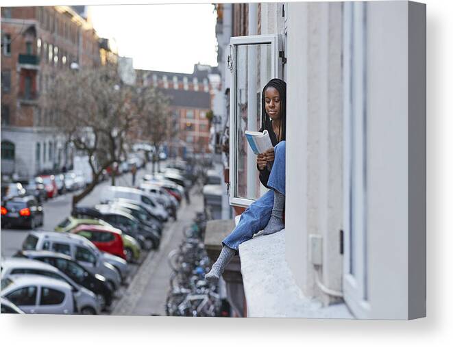 Prevention Canvas Print featuring the photograph Young woman reading book in apartment window by Klaus Vedfelt