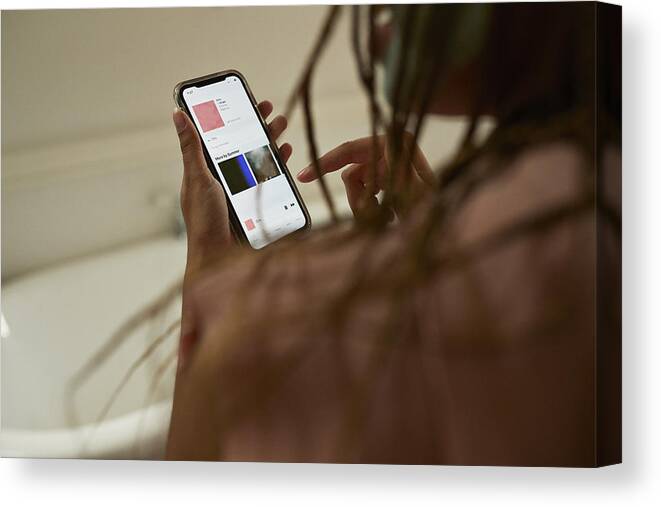 Internet Canvas Print featuring the photograph Young woman using smart phone in bathroom by Klaus Vedfelt