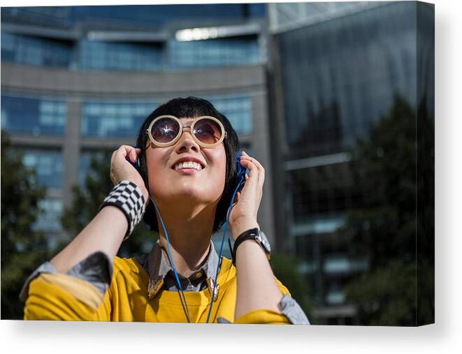 Cool Attitude Canvas Print featuring the photograph Young woman wearing sunglasses and headphones looking up by Steve Prezant