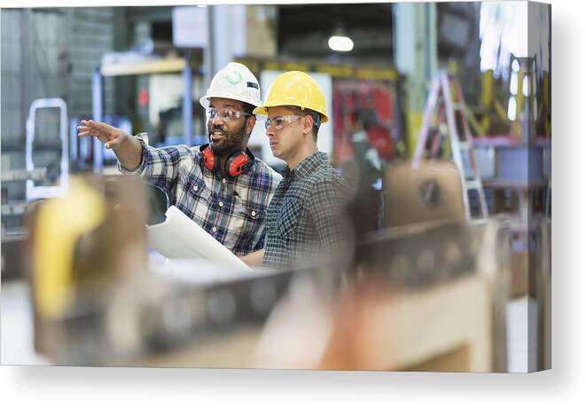 Working Canvas Print featuring the photograph Multi-ethnic workers talking in metal fabrication plant by Kali9