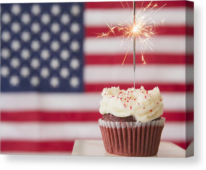Celebration Canvas Print featuring the photograph Studio shot of sparkler atop cupcake, american flag in background by Jamie Grill