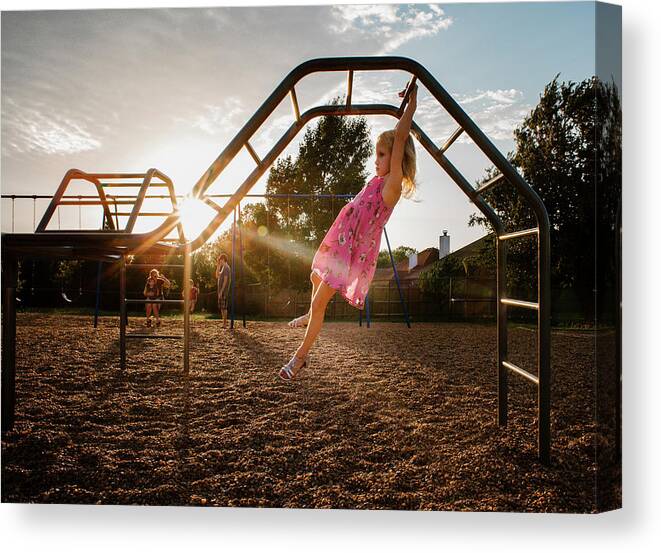 Girl Canvas Print featuring the photograph Side View Of Girl Hanging On Monkey Bars Against Sky At Playground During Sunset by Cavan Images