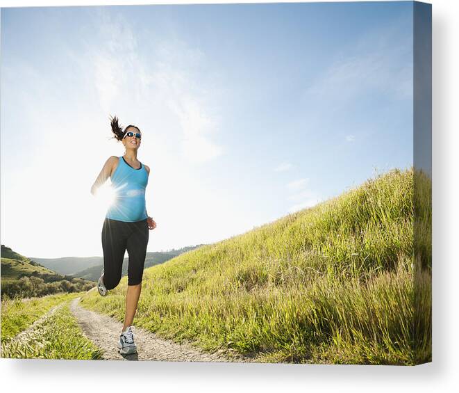 Mid Adult Women Canvas Print featuring the photograph Pregnant Hispanic woman running in remote area by Blend Images - Erik Isakson