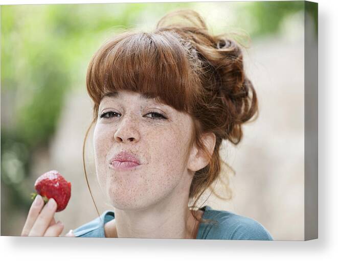 People Canvas Print featuring the photograph Germany, Berlin, Close up of young woman eating strawberry, smiling, portrait by Westend61