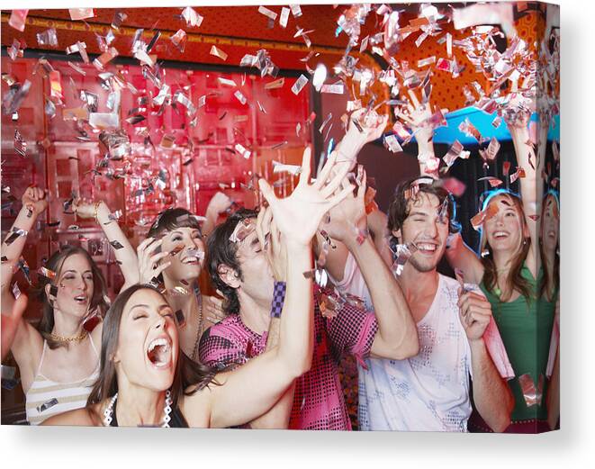 Young Men Canvas Print featuring the photograph Group of people in a nightclub partying and throwing confetti by Paul Bradbury
