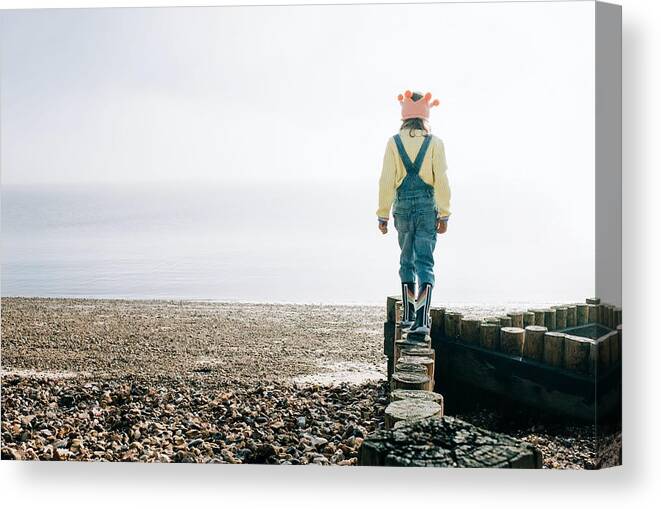 Beach Canvas Print featuring the photograph Child Balancing On Wooden Posts At The Beach Relaxing In The Sunshine by Cavan Images