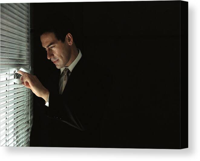 Corporate Business Canvas Print featuring the photograph Businessman looking through venetian blinds, portrait by Laurence Mouton