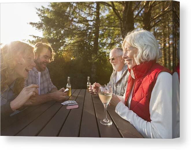 Mid Adult Men Canvas Print featuring the photograph Senior couple and adult children playing cards at campsite picnic table by Compassionate Eye Foundation/Steven Errico