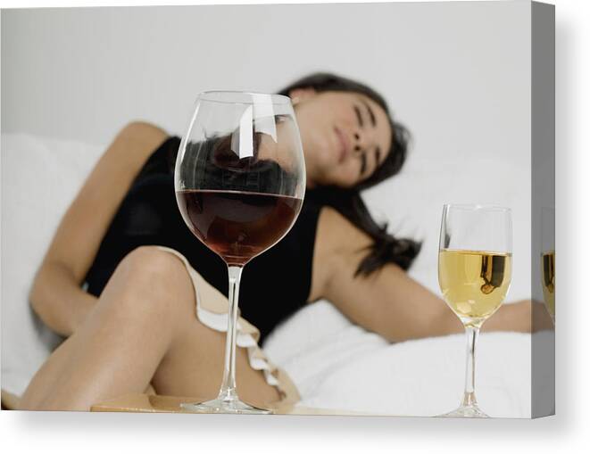Three Quarter Length Canvas Print featuring the photograph Young woman sleeping with wineglasses in front of her by Medioimages/Photodisc