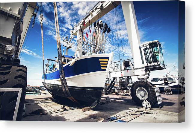 Blue Canvas Print featuring the photograph Fishing boat lifted by a boat lift by Jean-Luc Farges