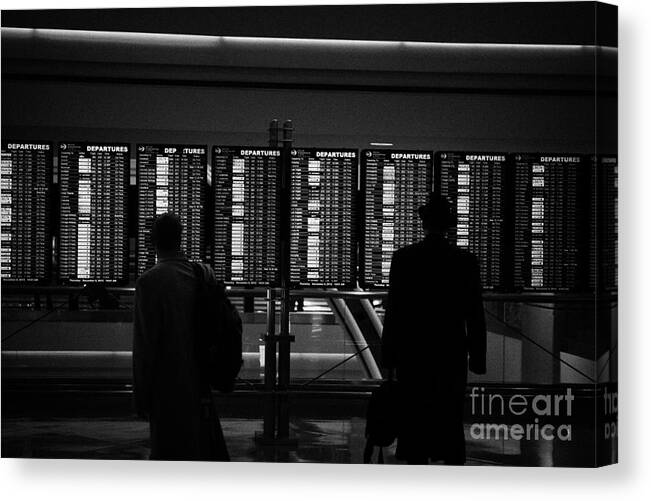Departures Canvas Print featuring the photograph passengers looking at departures board at Denver International Airport Colorado USA by Joe Fox