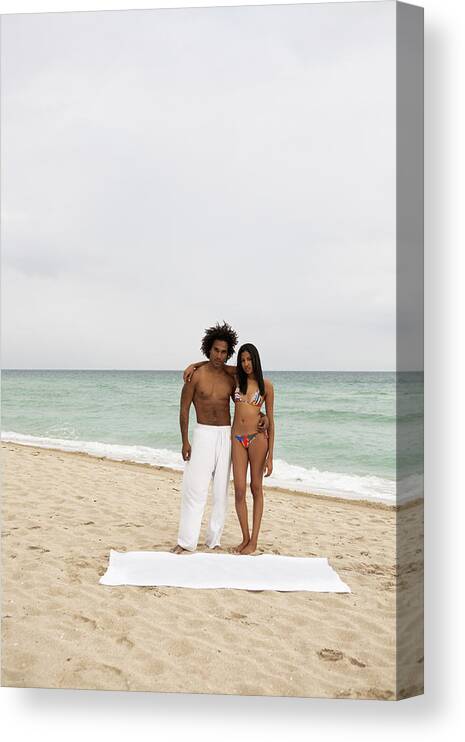 Young Men Canvas Print featuring the photograph An attractive young couple standing on a beach by Emiliano Granado