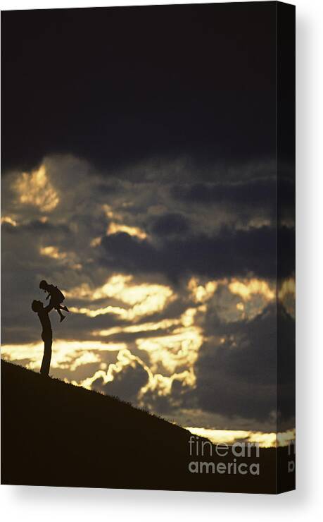 Silhouetted Canvas Print featuring the photograph Father holding daughter above his head along hillside silhouette by Jim Corwin