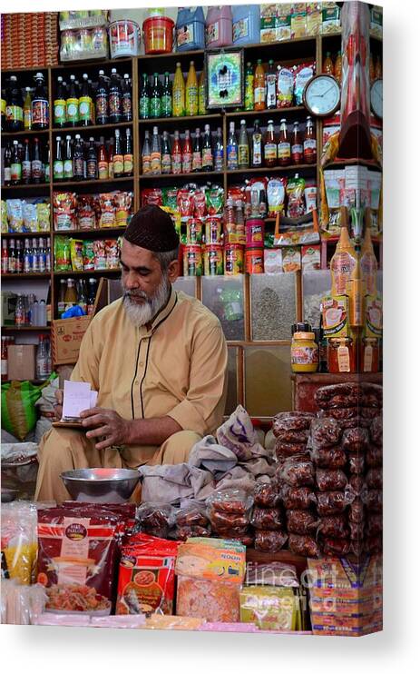 Man Canvas Print featuring the photograph General store keeper tends to paperwork at Empress Market Karachi Pakistan by Imran Ahmed
