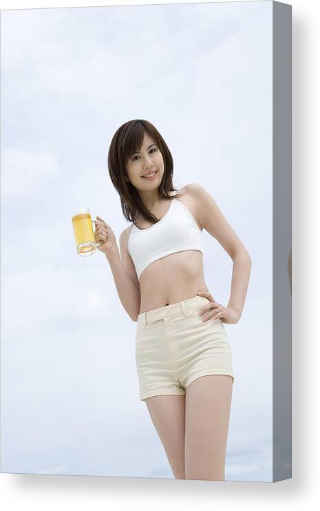 People Canvas Print featuring the photograph Young woman holding a beer glass, low angle view by Daj