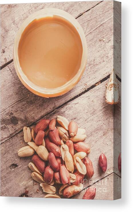 Peanuts Canvas Print featuring the photograph Peanut butter jar with peanuts on wooden surface by Jorgo Photography