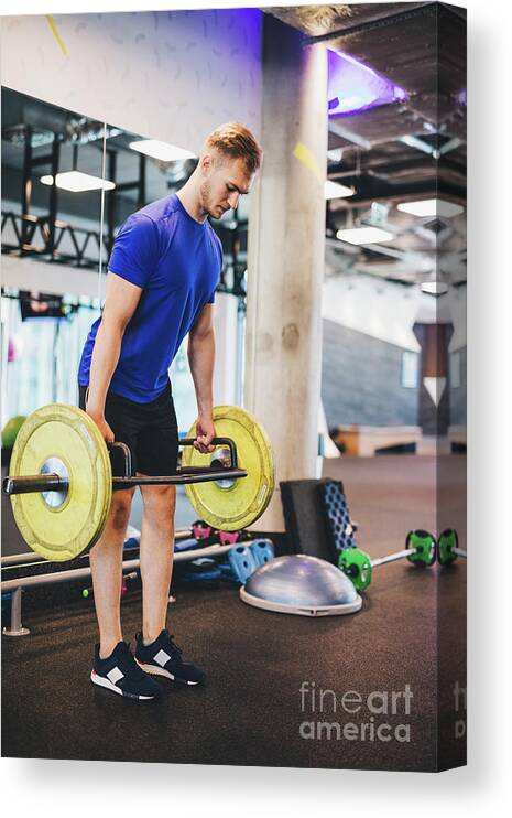 Man Canvas Print featuring the photograph Man working out at the gym, lifting weights. by Michal Bednarek