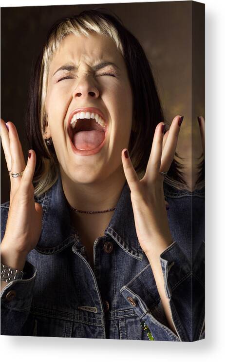 Caucasian Ethnicity Canvas Print featuring the photograph A Caucasian Young Woman With Brown And Blond Streaked Hair Wearing A Jean Jacket Is Screaming With Eyes Closed And Hands Raised Near Her Face by Photodisc