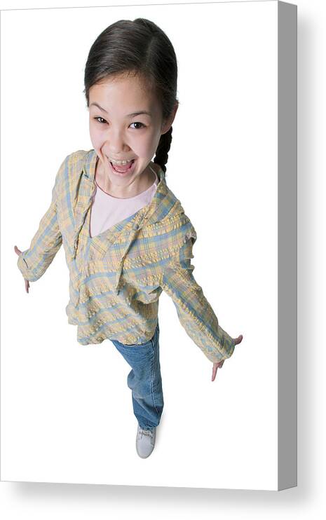 Child Canvas Print featuring the photograph A Young Asian Girl In Jeans And A Green Shirt As She Spreads Out Her Arms And Smiles Up Into The Camera by Photodisc