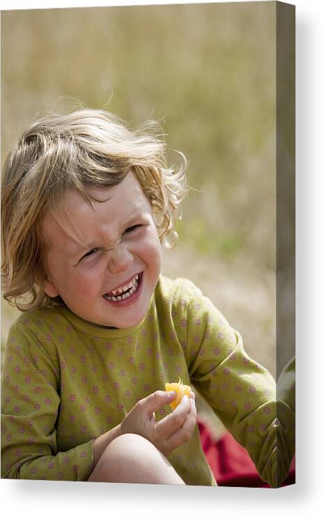 Toddler Canvas Print featuring the photograph Girl eating fruit and laughing by Comstock Images