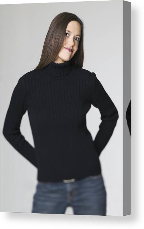 White Background Canvas Print featuring the photograph Medium Shot Of A Young Adult Woman In A Black Sweater As She Puts Her Hands On Her Hips And Smiles by Photodisc