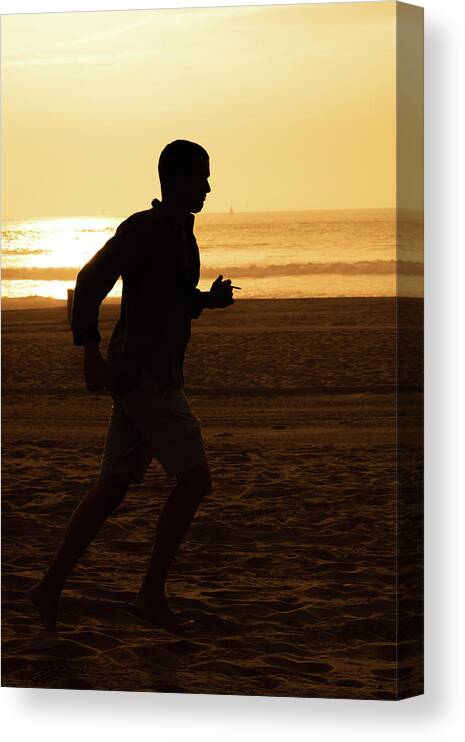 Silhouette Canvas Print featuring the photograph Silhouette of a tall man running on beach at sunset stock photo by Mark Stout