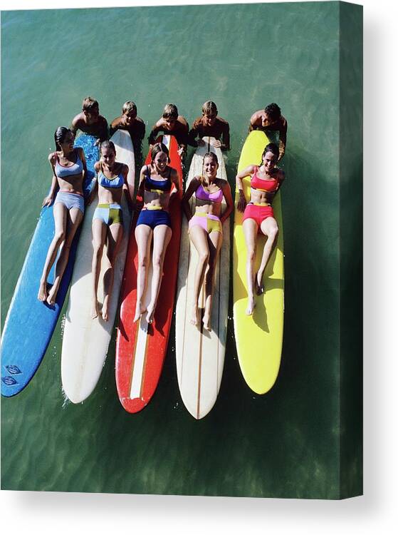 Fashion Canvas Print featuring the photograph Models Wearing Bikinis Lying On Surfboards by William Connors