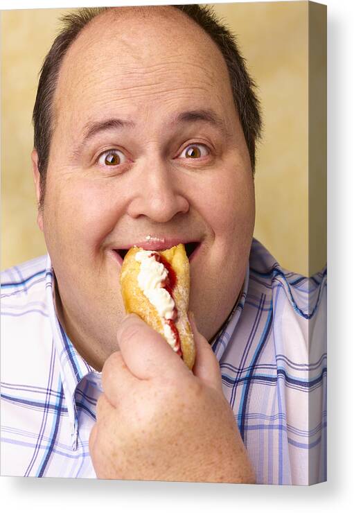Holding Canvas Print featuring the photograph Obese man eating cream cake. by Peter Dazeley