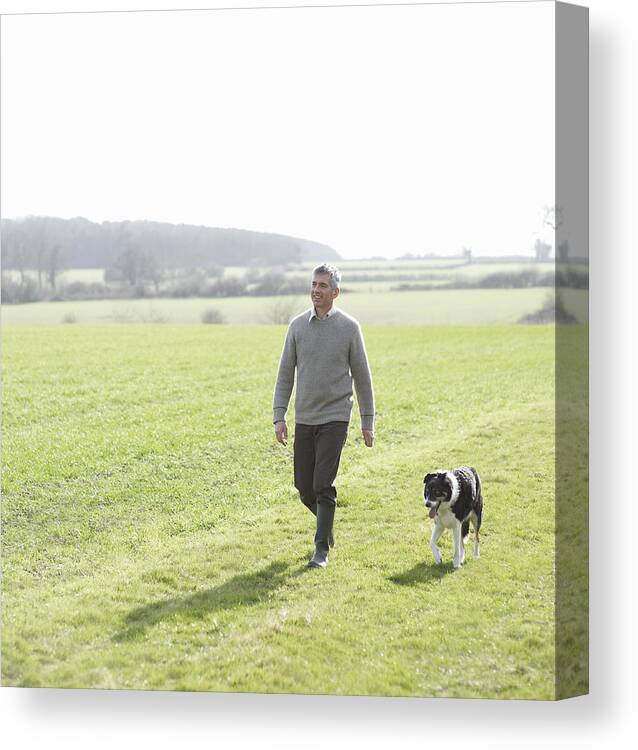 Pets Canvas Print featuring the photograph Man walking in countryside with pet dog by Dougal Waters