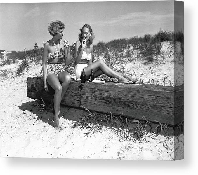 Grass Canvas Print featuring the photograph Two Women In Bikini Eating Snack On by George Marks