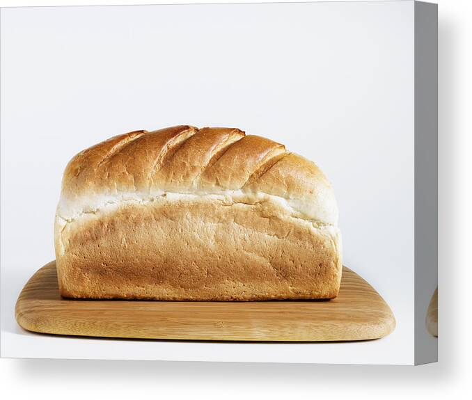 White Background Canvas Print featuring the photograph Loaf of bread on chopping board, close-up by Diamond Sky Images