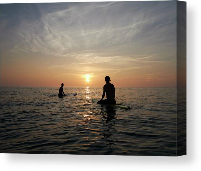 Young Men Canvas Print featuring the photograph Surfers Sitting On Boards At Sunset by Dougal Waters