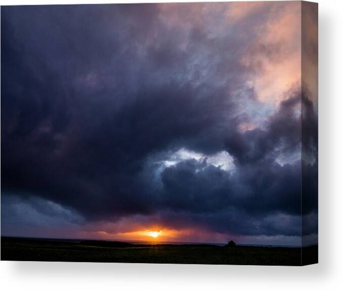 Sunset Canvas Print featuring the photograph Glowing Sun Setting Under Storm Clouds by Cavan Images