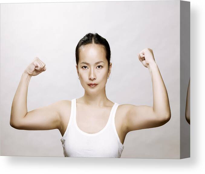 People Canvas Print featuring the photograph Young asian woman flexing her muscles by Ballyscanlon