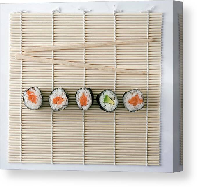 White Background Canvas Print featuring the photograph Sushi And Chopsticks On A Wooden Mat by Larry Washburn