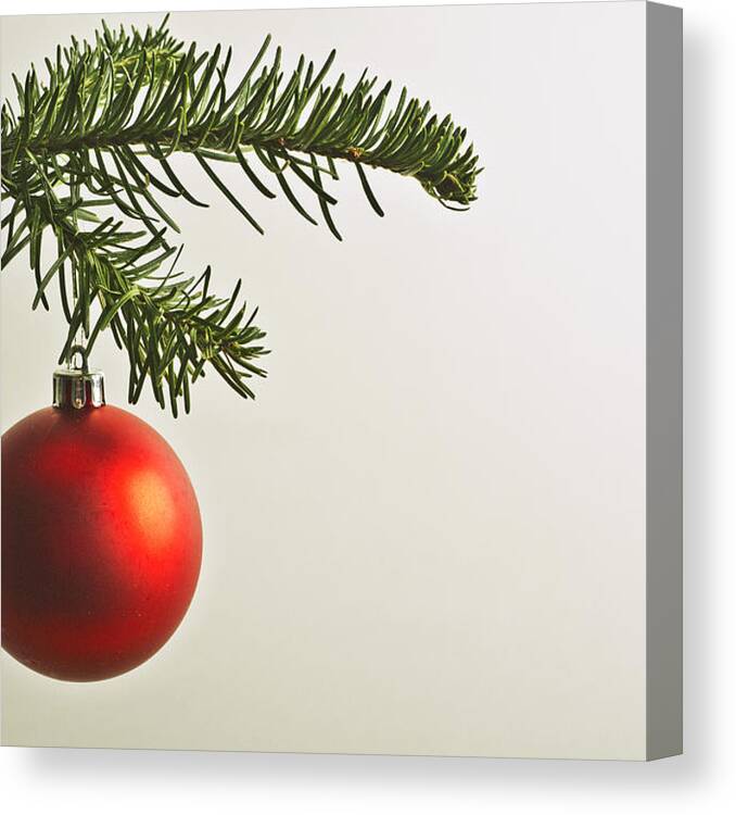 Hanging Canvas Print featuring the photograph Red Christmas bauble hanging from Christmas tree by PhotoAlto/Michele Constantini