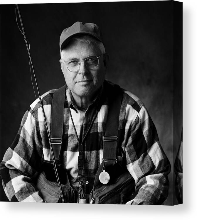 Baseball Cap Canvas Print featuring the photograph A caucasian elderly man sits in his fly fishing gear by Photodisc