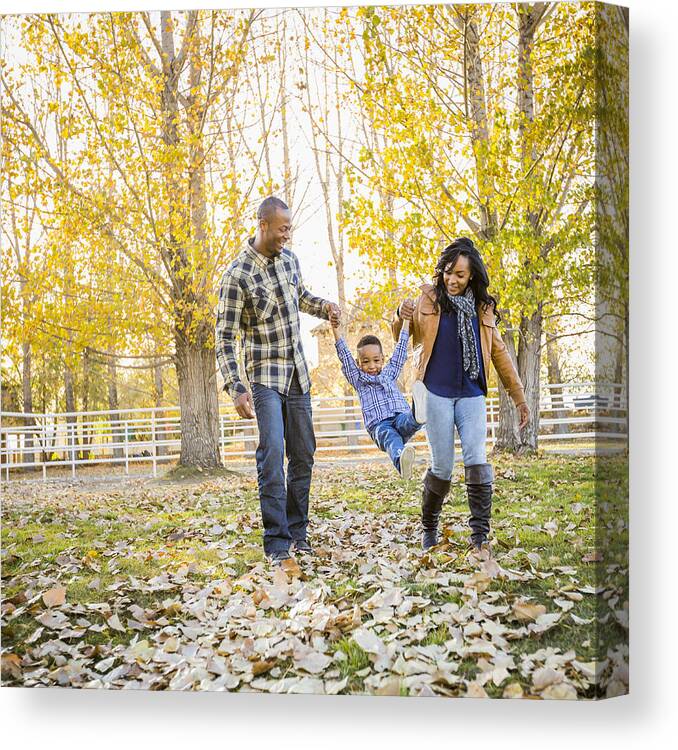Hanging Canvas Print featuring the photograph Black family playing in autumn leaves by Mike Kemp