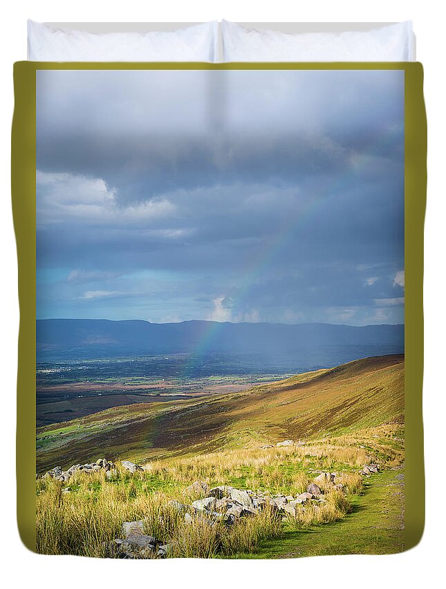 Blue Duvet Cover featuring the photograph Sunshine and raining down with rainbow on the countryside in Ire by Semmick Photo