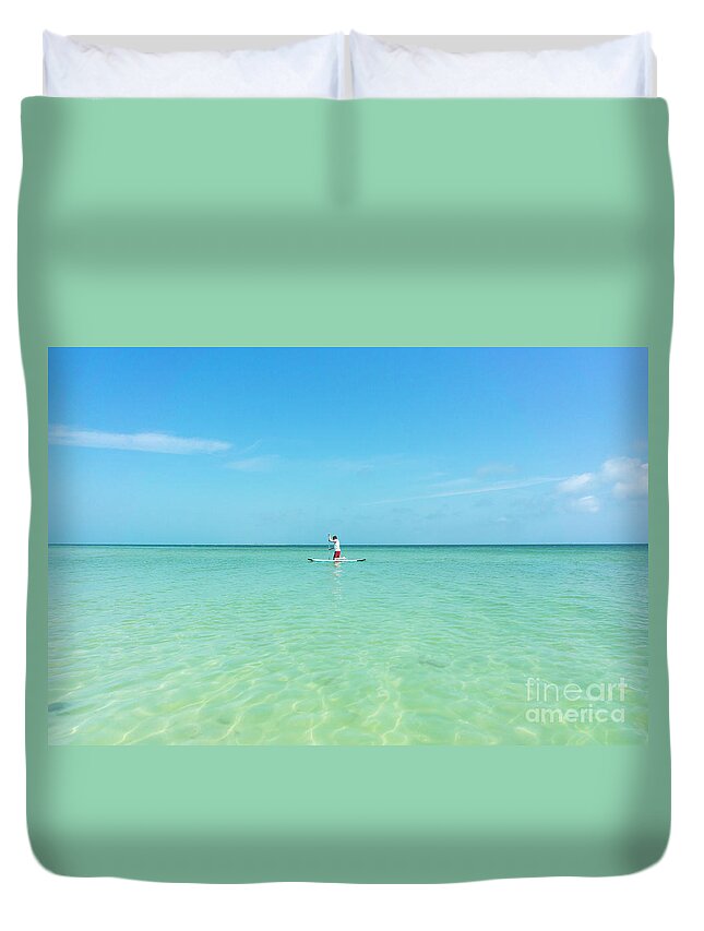 Anna Maria Island Duvet Cover featuring the photograph A man rides a paddleboard in the shallow waters near the city pi by William Kuta