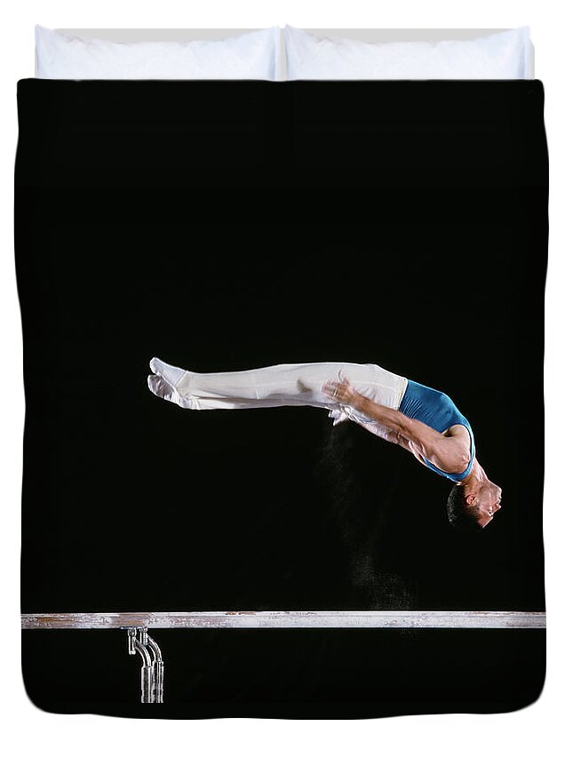 One Man Only Duvet Cover featuring the photograph Male Gymnast Performing On Parallel Bars by David Madison