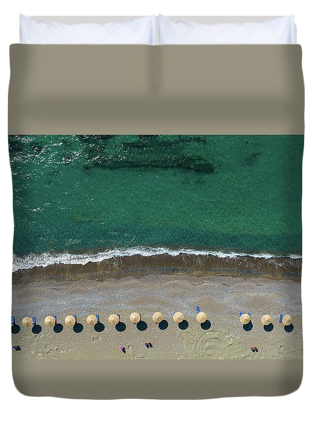 Summertime Duvet Cover featuring the photograph Aerial view from a flying drone of beach umbrellas in a row on an empty beach with braking waves. by Michalakis Ppalis