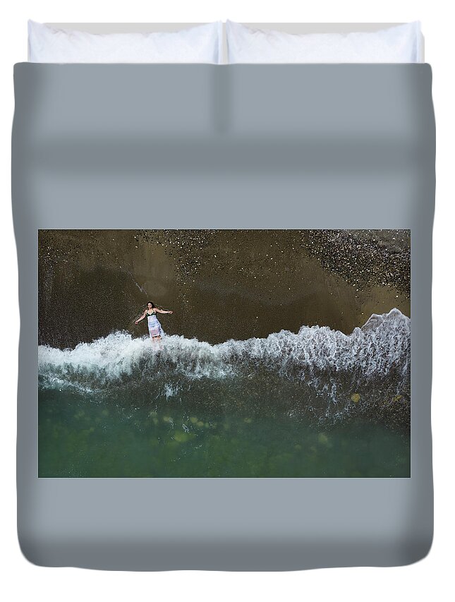 Holidays Duvet Cover featuring the photograph Woman with white dress resting on a sandy beach with braking waves on the shore. Overhead shot. Aerial drone photograph by Michalakis Ppalis
