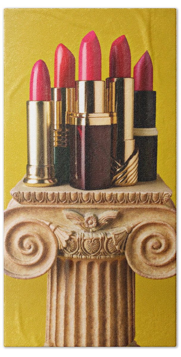 Cosmetics Bath Towel featuring the photograph Five red lipstick tubes on pedestal by Garry Gay