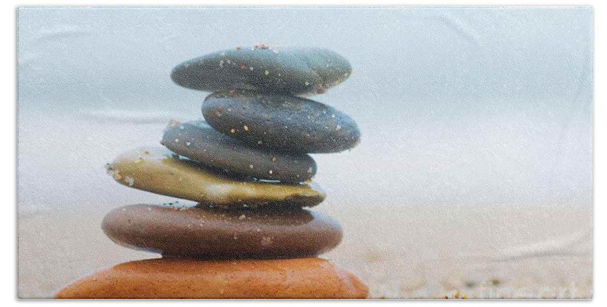 Stone Hand Towel featuring the photograph Stack of beach stones on sand by Michal Bednarek