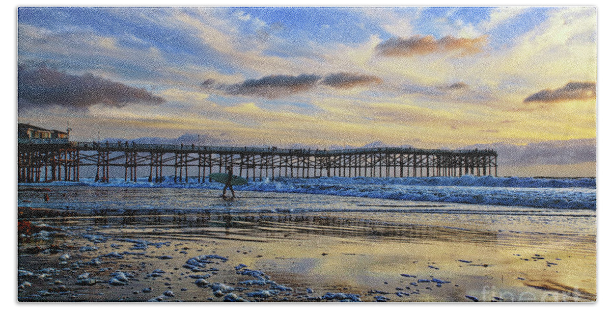 Pacific Beach Bath Towel featuring the photograph A surfer heads home under a cloudy sunset at Crystal Pier by Sam Antonio
