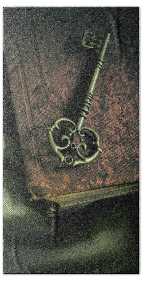 Key Hand Towel featuring the photograph Brass ornamented key on old brown book by Jaroslaw Blaminsky