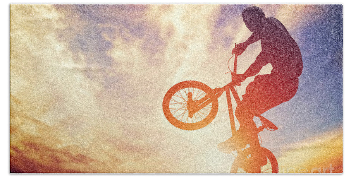 Bike Bath Towel featuring the photograph Man riding a bmx bike performing a trick against sunset sky by Michal Bednarek