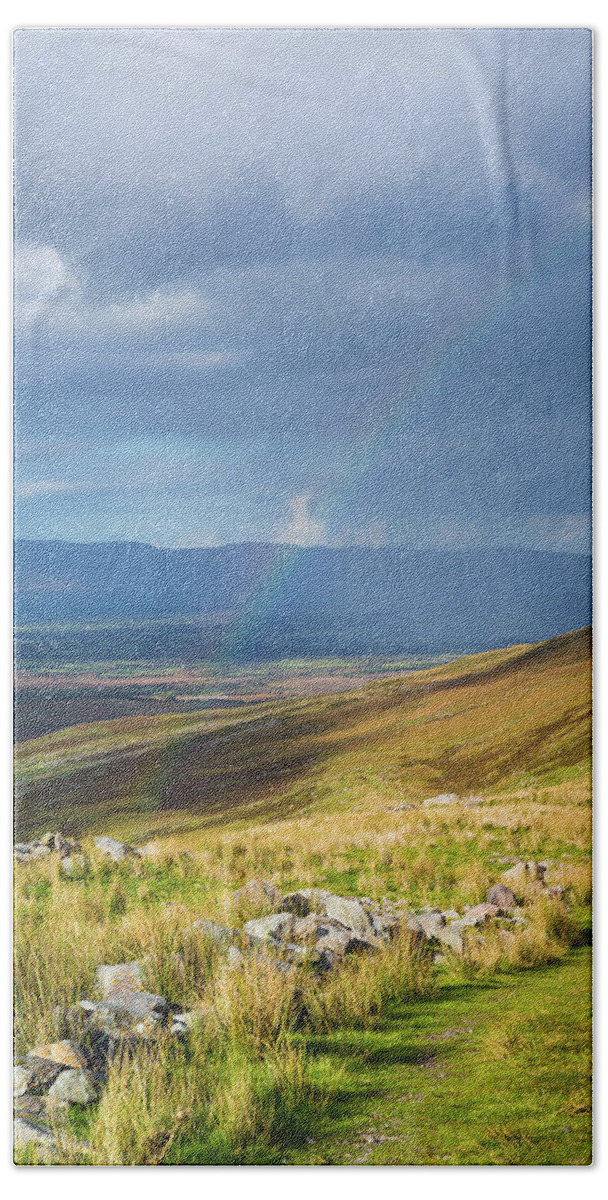 Blue Bath Towel featuring the photograph Sunshine and raining down with rainbow on the countryside in Ire by Semmick Photo